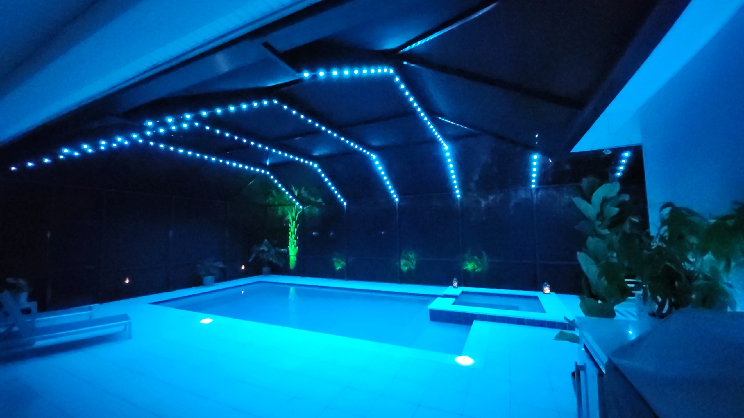 Pinellas County pool cage at night with saturated blue LED puck lights on the large aluminum beams