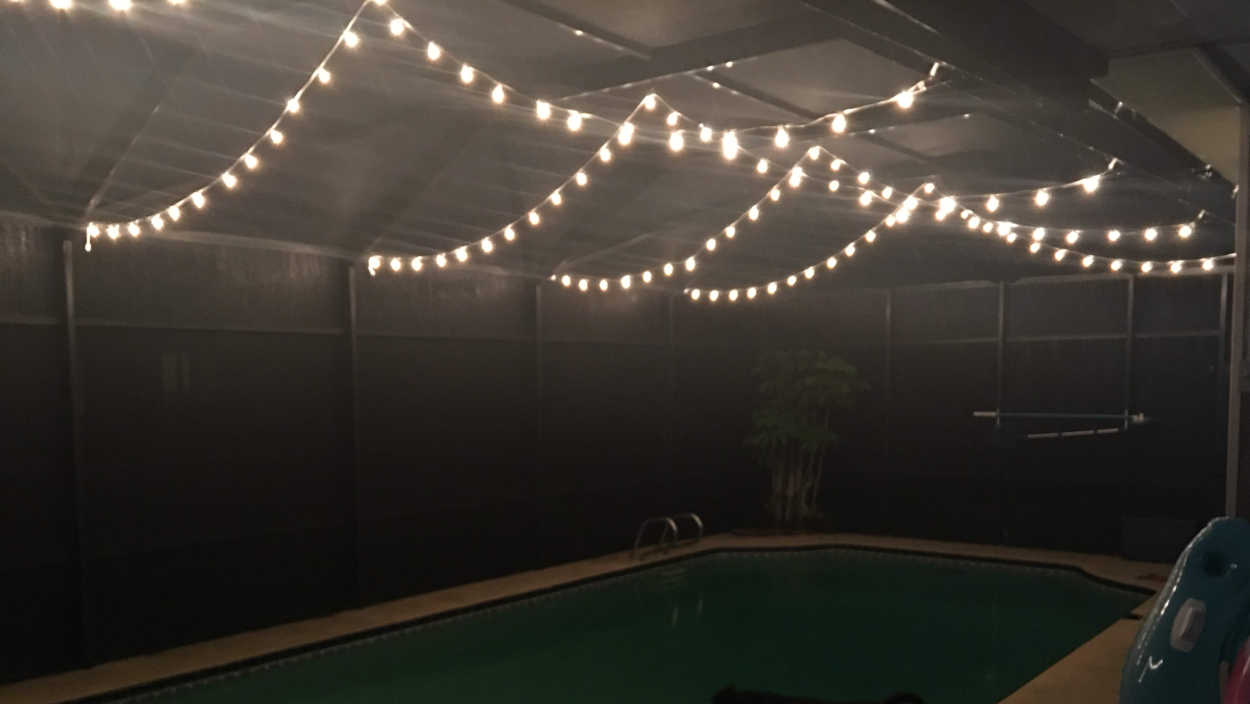 Sagging plug-in string lights hanging over a pool cage — the look permanent pucks replace